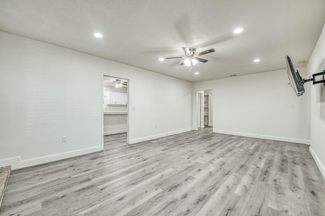 unfurnished living room with ceiling fan, a textured ceiling, and light hardwood / wood-style floors