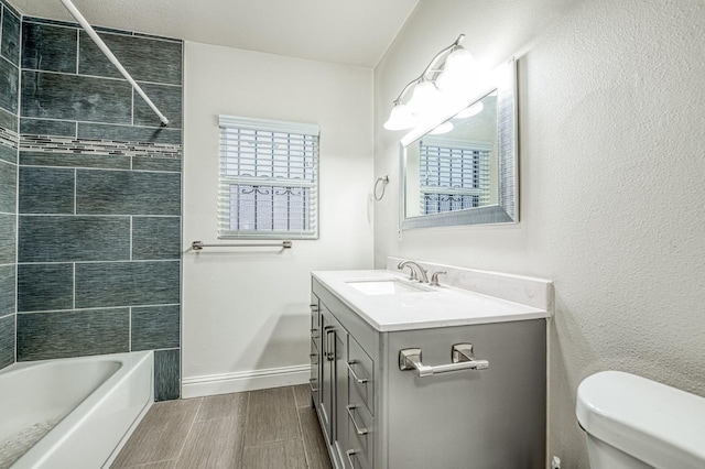 full bathroom featuring tiled shower / bath, hardwood / wood-style floors, vanity, and toilet