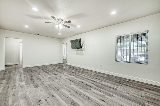 empty room with light wood-type flooring, ceiling fan, and a textured ceiling