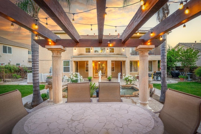 patio terrace at dusk featuring area for grilling and a balcony