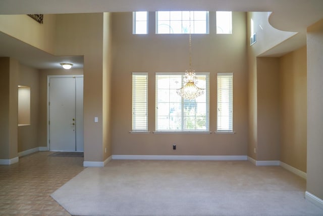 carpeted entryway featuring a high ceiling and a chandelier