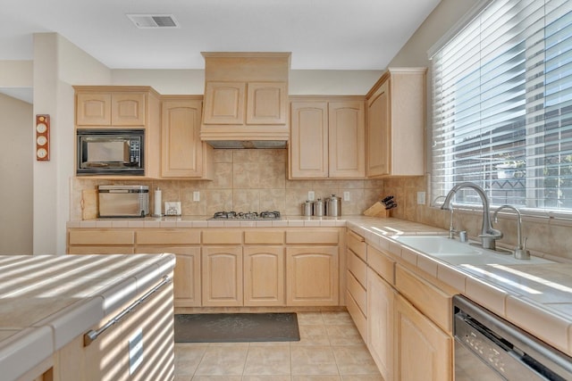 kitchen with light brown cabinetry, appliances with stainless steel finishes, and tile countertops