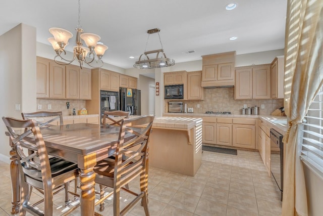 kitchen featuring tasteful backsplash, light brown cabinets, decorative light fixtures, tile counters, and black appliances