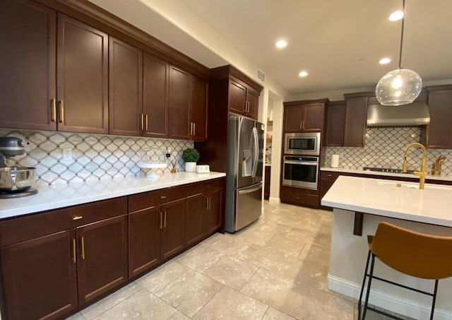 kitchen featuring tasteful backsplash, pendant lighting, wall chimney exhaust hood, and stainless steel appliances