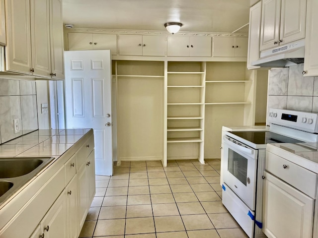 kitchen featuring white range with electric cooktop, light tile patterned flooring, white cabinets, and tile countertops