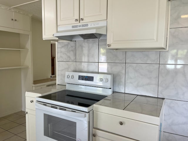 kitchen with electric stove, white cabinetry, and light tile patterned flooring