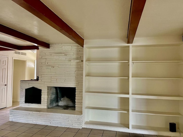 unfurnished living room featuring tile patterned floors, a stone fireplace, and beamed ceiling