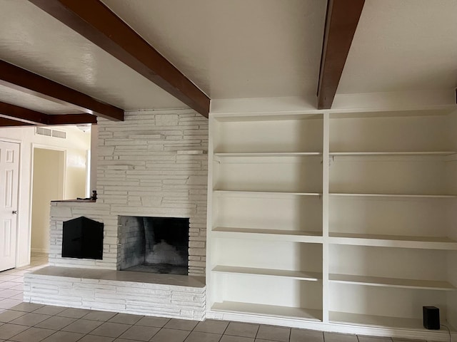 unfurnished living room featuring a fireplace, beamed ceiling, and tile patterned flooring