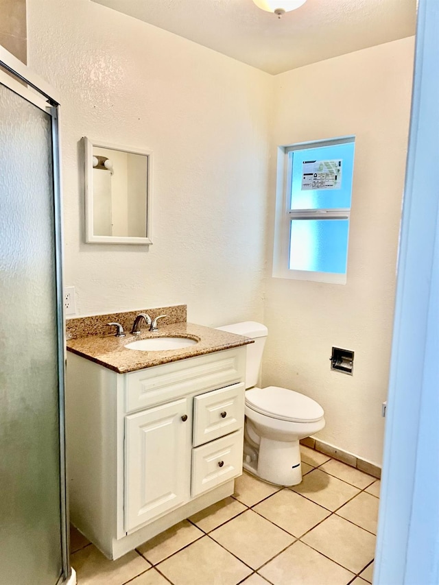 bathroom with tile patterned flooring, vanity, toilet, and a shower with shower door