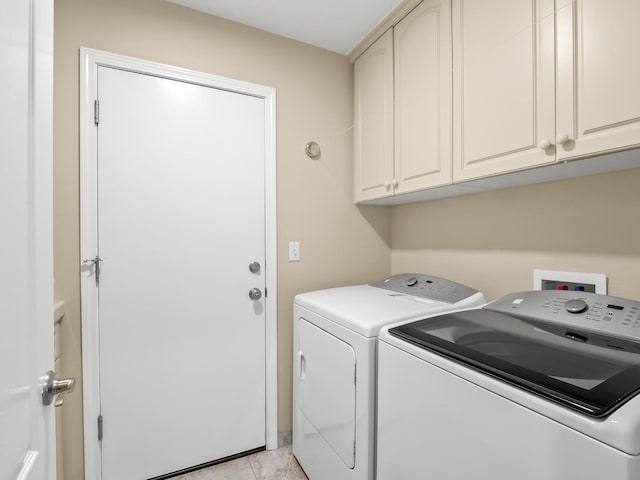 laundry room with light tile patterned flooring, cabinets, and separate washer and dryer