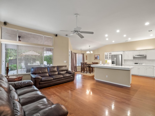 living room featuring lofted ceiling, sink, light hardwood / wood-style floors, and ceiling fan with notable chandelier