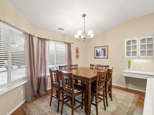 dining area featuring a chandelier, vaulted ceiling, and light hardwood / wood-style floors