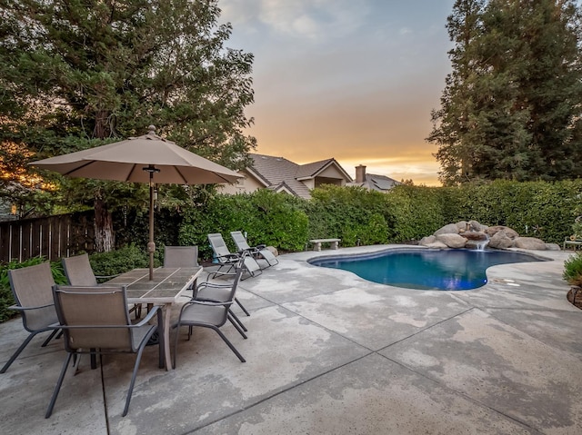 pool at dusk with a patio area