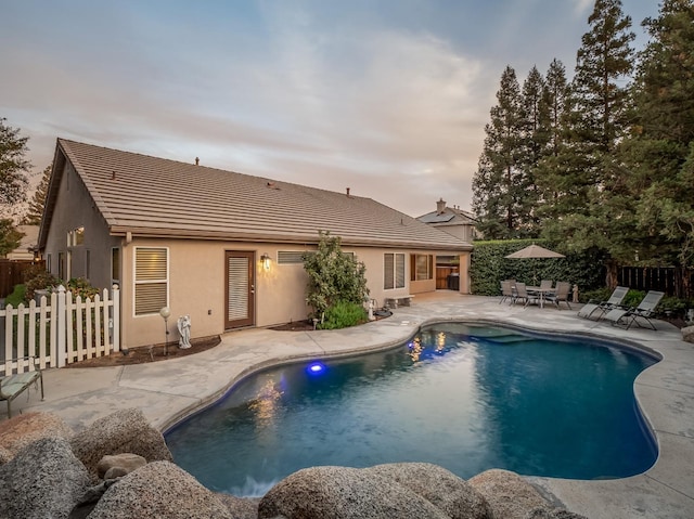 pool at dusk with a patio