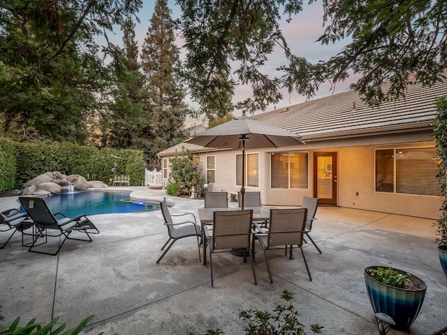 patio terrace at dusk featuring a fenced in pool