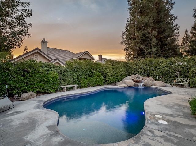 pool at dusk featuring a patio