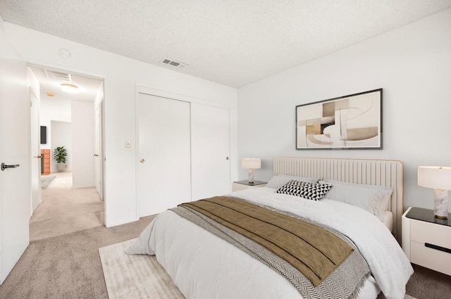 carpeted bedroom with a textured ceiling and a closet