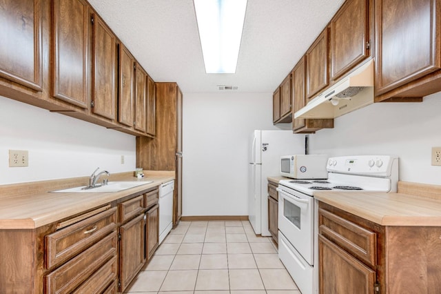 kitchen featuring white appliances, sink, a textured ceiling, and light tile patterned floors