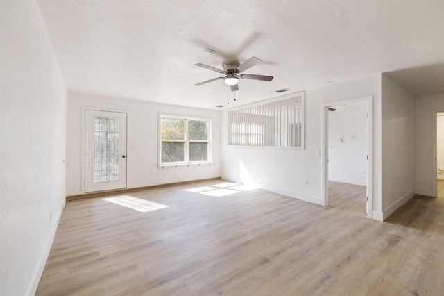 empty room with a textured ceiling, light wood-type flooring, and ceiling fan