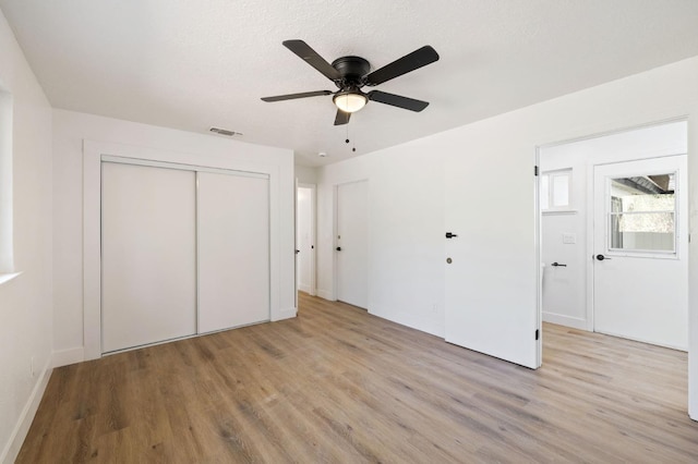 unfurnished bedroom featuring a closet, light hardwood / wood-style floors, a textured ceiling, and ceiling fan