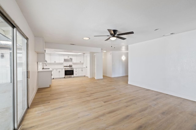 unfurnished living room with sink, light wood-type flooring, and ceiling fan