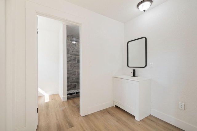 bathroom featuring hardwood / wood-style floors, tiled shower, and vanity