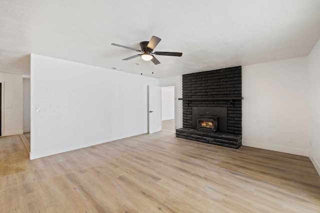 unfurnished living room with ceiling fan, a fireplace, and light hardwood / wood-style floors