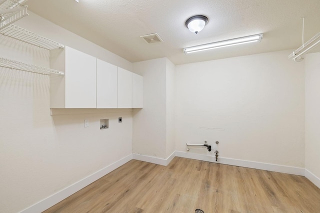 laundry room with light hardwood / wood-style floors, electric dryer hookup, washer hookup, gas dryer hookup, and cabinets