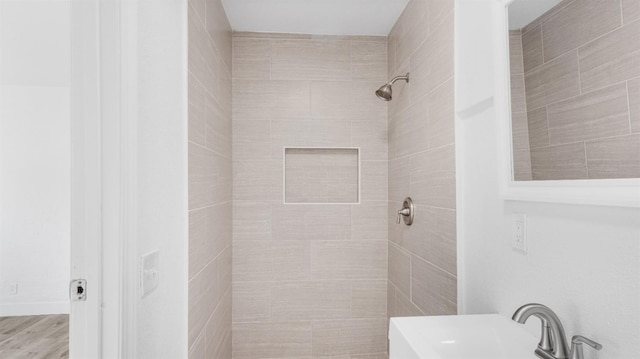 bathroom featuring hardwood / wood-style flooring, sink, and a tile shower