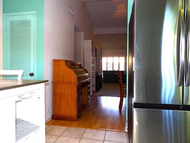 kitchen with light tile patterned flooring, lofted ceiling, and stainless steel refrigerator