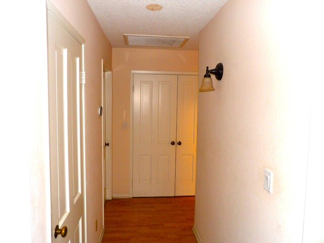 corridor with hardwood / wood-style flooring and a textured ceiling