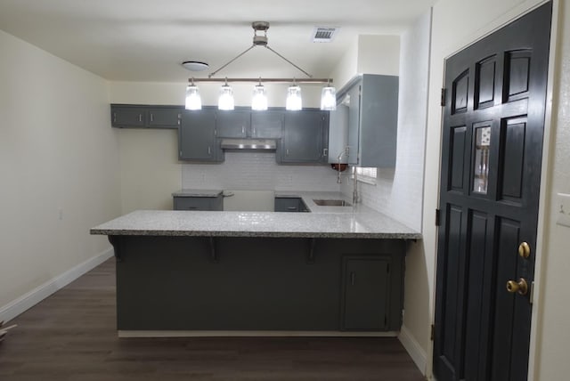 kitchen with gray cabinetry, dark hardwood / wood-style flooring, sink, decorative backsplash, and kitchen peninsula