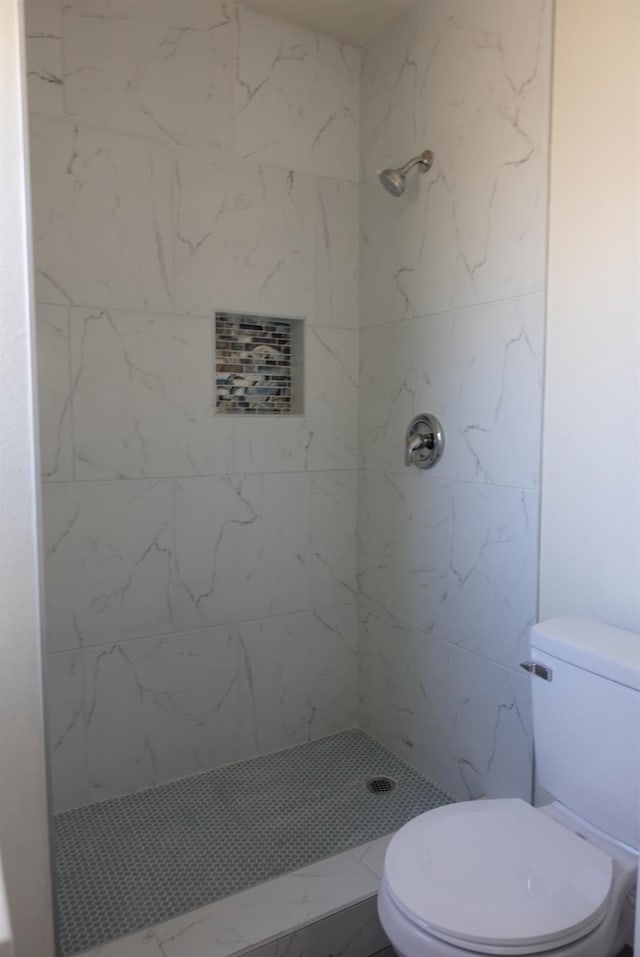 bathroom featuring a tile shower and toilet