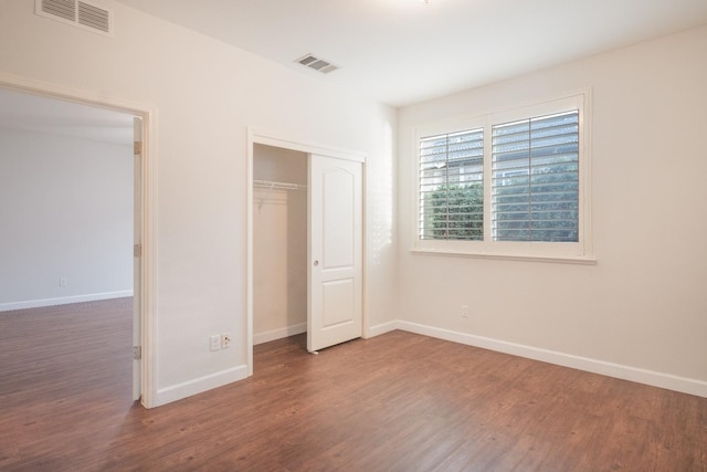 unfurnished bedroom with a closet and dark hardwood / wood-style flooring