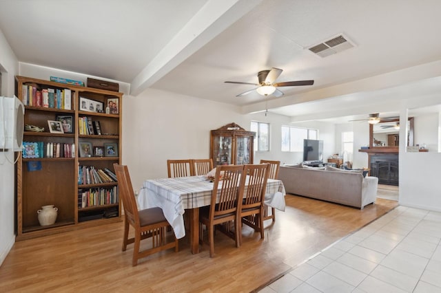 dining space with light hardwood / wood-style floors, beamed ceiling, and ceiling fan