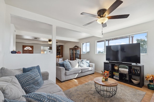 living room featuring light hardwood / wood-style floors, ceiling fan, and beam ceiling