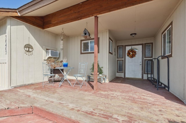 view of exterior entry featuring a wall mounted air conditioner and a patio area