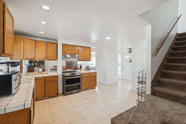 kitchen featuring tile counters, appliances with stainless steel finishes, and light tile patterned flooring