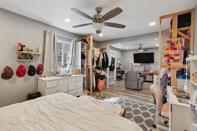 bedroom with light wood-type flooring, ceiling fan, and a closet
