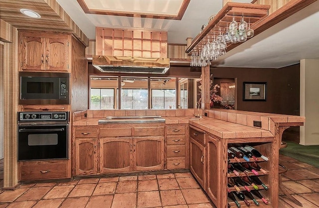 kitchen featuring sink, tile countertops, kitchen peninsula, and black appliances