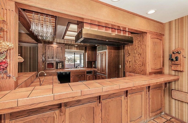 kitchen featuring a notable chandelier, sink, tile counters, dishwasher, and exhaust hood