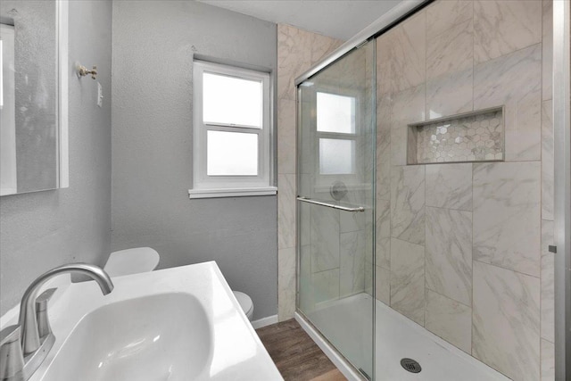 bathroom featuring hardwood / wood-style flooring, toilet, a shower with door, and sink