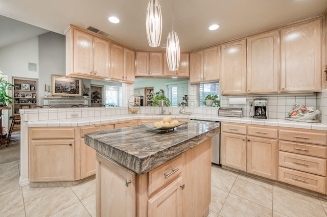 kitchen featuring kitchen peninsula, a kitchen island, and light brown cabinetry