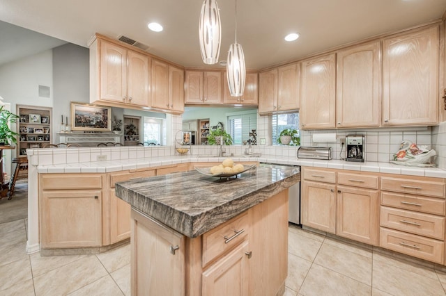 kitchen featuring visible vents, light tile patterned floors, light brown cabinets, dishwasher, and a kitchen island
