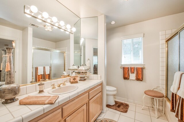 bathroom with visible vents, toilet, vanity, tile patterned floors, and a shower with door