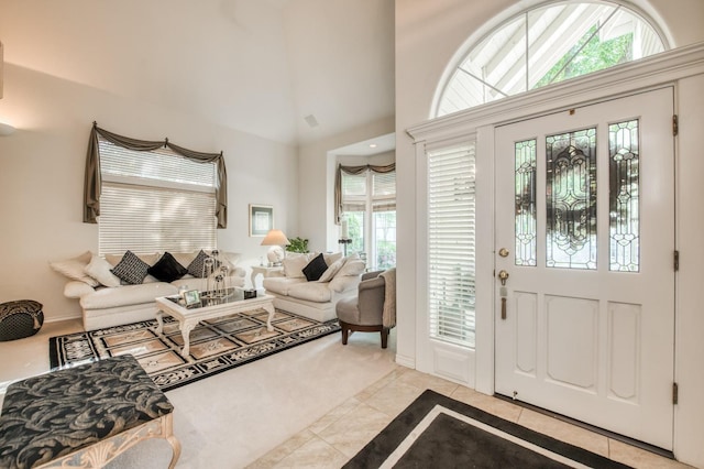 entryway featuring light carpet, light tile patterned floors, a towering ceiling, and baseboards