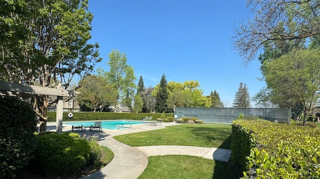 pool featuring a patio, fence, and a lawn