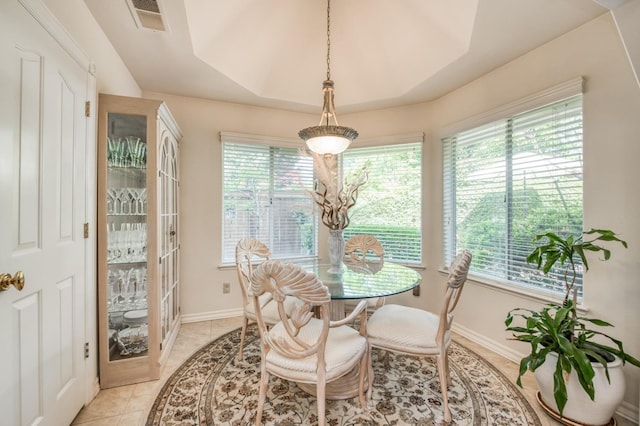 dining area with light tile patterned floors, visible vents, baseboards, and a raised ceiling
