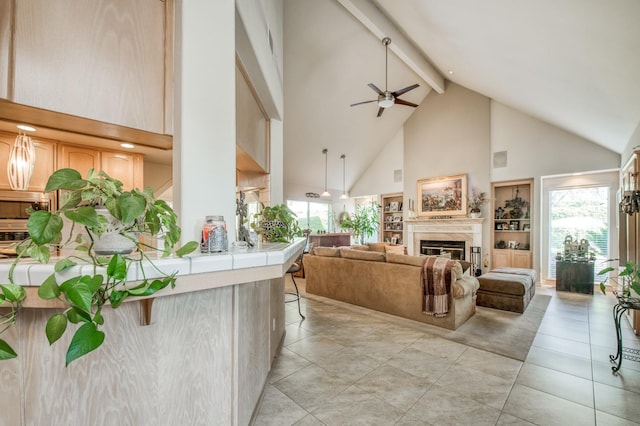 living room with ceiling fan, light tile patterned floors, beam ceiling, and high vaulted ceiling