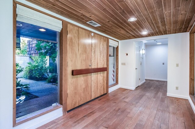 empty room featuring baseboards, visible vents, wood finished floors, and wood ceiling